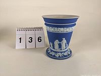 Front view of blue and white Wedgwood Jasperware cache pot next to a number stand