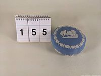 Light blue Wedgwood jasperware trinket box shown next to a number board indicating lot number