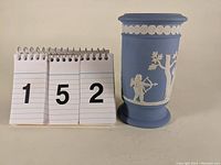 Front view of light blue Wedgwood Jasperware vase with white classical relief detail.