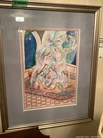 Frontal view of the framed watercolor painting showing the full composition of winged figures on a rug.