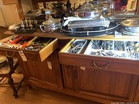 Two wooden drawers open showing assorted cutlery and kitchen utensils inside plastic trays.