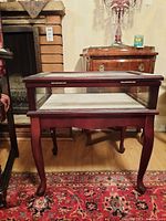 Front view of wood and glass display table showing glass top and wooden legs.