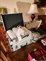 Photo of an open aluminum case showing several bubble-wrapped ribbed cylindrical glass shades inside.