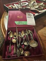 Open case showing spoons inside and additional spoons on tray