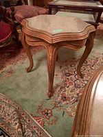 Set of two decorative wood frame side tables with stone tops, shown on carpeted floor among other furniture.