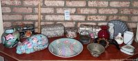 Wide view showing full lot on shelf with brick background, featuring ceramic boxes, cat figurine, pots, vases, basket, and plate