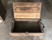 Wooden crate opened to show interior and lid construction, showing wear and metal clasp.