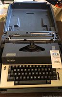 Olympia electric typewriter inside open portable hard case, viewed from above, showing keys and typebars