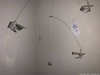 Close up photo of two silver hang gliders suspended on translucent filament with a metal supporting wire and a silver weight ball for balance.