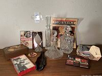 Full display of bar lot items including glass decanters, perfume bottle, books, vintage matches, spoon rest, and decorative box.