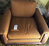 Front view of chair showing gold-brown textured upholstery and wooden armrests and legs. Seller label and dimensions 34x33x26.5 visible on seat cushion.