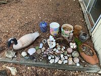 Full lot overview showing arrangement of porcelain pots, decorative stones, shells, and figurines including the goose and terra-cotta fish planter