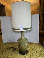 Full view of vintage olive green ceramic lamp with white flecked cylindrical shade on top.