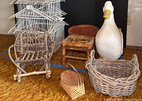 Wide shot of entire lot showing bird cage, chair, baskets, painted wooden goose, and bamboo tool on orange carpet.