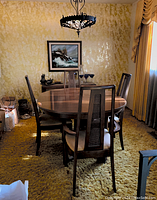 Full set of walnut dining table surrounded by four rattan-back chairs in room setting