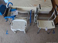 Wide view showing all items: 2 bath chairs, 1 sliding bath chair, and 3 bed rails arranged on floor near bed mattress.