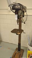 Front full view of the Delta drill press showing entire unit including base, stand, worktable, motor and controls.
