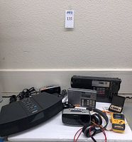 Overview of six items: Bose Wave radio, Brookstone digital alarm clock, Sony ICF-2002 portable FM receiver, Sony FM/AM synthesizer receiver ICF-2001, Sony Sports Walkman cassette player with headphones, quartz portable alarm clock