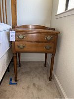 Full front view showing two drawers, turned legs, and open area below drawers