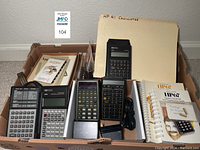 Overview of four calculators, manuals, card reader, power cable and boxes/folders