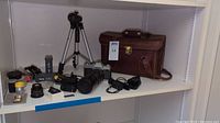 Wide shot showing Mamiya camera with long zoom lens, two Walters scopes, tripod, leather bag, film safes and accessories on shelf