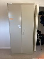 Front view of the closed metal cabinet showing the double doors and lock keyhole.