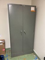 Full front view of grey metal cabinet with double doors and handles.