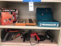 Shelf with boxed Black & Decker 12V cordless drill, Craftsman electric sander, Milwaukee 1/2 hammer drill, Black & Decker belt sander, and corded power tools below with accessories.