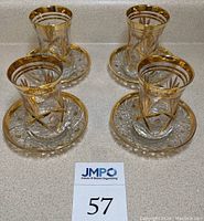 Full set of four Turkish coffee/tea glasses and four matching cut glass saucers with gold accents.