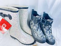 Tall white boots with multicolored speckles next to short black floral lace-up boots in pair view