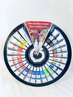 Top view of circular tray with 24 tubes of new acrylic paint in various colors.