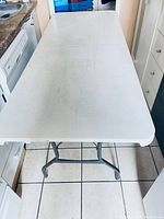 Top-down photo of folding table showing the full white plastic surface and scuff marks.
