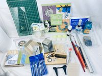 Photo of metal clay kit items laid out showing instructional book, work surfaces, various tools, brushes, and compounds.