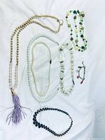 Photo showing six various necklaces laid out flat including ruler for scale