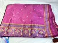 Top view of folded deep purple sari fabric showing decorative woven border along width and length and small multicolored motifs.