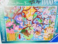 Close-up of completed puzzle box front showing colorful birds, cherry blossoms, and Chinese lanterns.