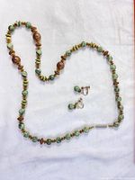 Necklace and earrings laid out on white cloth, showing bead details and arrangement