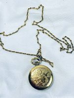 Full view of pocket watch on chain laid on white background