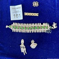 Photo showing all items: East Indian silver toned anklet, long gold pin, vintage sapphire pin, and two unmatched earrings arranged on blue velvet background.