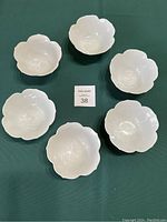 Top view showing set of 6 white lotus-shaped bowls arranged on a green surface.