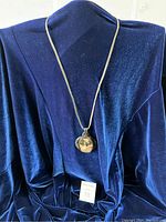 Full view of the necklace displayed on a blue velvet dress form showing the pendant hanging at mid-chest length.