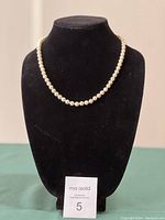 Full view of pearl necklace displayed on black velvet bust