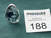 Front angle close-up showing translucent stone with moss-like inclusions in silver-tone bezel setting on ring band.