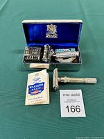 Full view of Wilkinson razor kit with open travel tin containing blade holder, razor, and instruction leaflet outside with auction tag