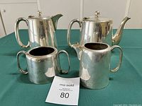 Silver plated Sheffield EPNS tea and coffee set including coffee pot, teapot, cream jug and sugar bowl displayed on a green cloth surface.