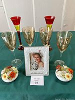 Photo showing four amber-tinted wine glasses with floral design, two tall red wine glasses, a white anniversary picture frame, and two Bone China candle holders with floral decoration and raised flowers
