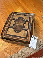 Open view of the antique German Bible in a box showing the cover with embossed floral designs and the title 'Heilige Schrift'