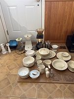 Overall view of Bavarian porcelain dinnerware and various kitchen appliances arranged on floor.