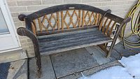 Front view of metal and wood garden bench with decorative backrest and curved armrests