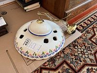 Top view of the ceramic ceiling fixture showing the brass mounting arm and white ceramic shade with ventilation cutouts.